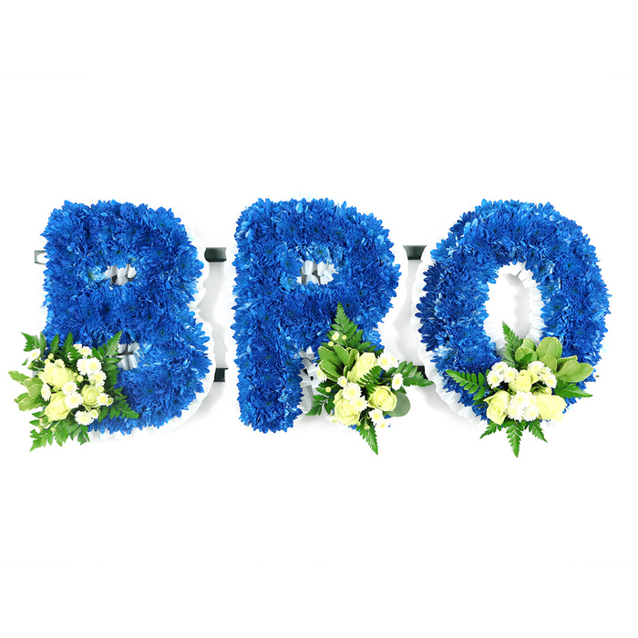 Presented against a clean white studio backdrop, this three-piece memorial spells BRO in bold capital letters, each formed from a dense carpet of deep royal blue chrysanthemums. The blooms are so closely packed they read like velvety panels, the colour intense and even across each letter's surface. At the lower portions of B, R and O sit composed clusters of delicate cream-to-pale-yellow spray roses, edged with small white filler flowers such as mini chrysanthemums or baby's breath, their soft shapes offering a gentle counterpoint to the saturated blue. Intertwined foliage - broader glossy leaves reminiscent of salal and lighter, airy fern fronds - provides texture, volume and a subtle green fragrance. A neat white base or foam frame traces the outer edges and the interior voids of the letters, indicating the sturdy construction that allows these freestanding tributes to be displayed at chapels and hearses. The overall impression is one of respectful dignity: royal blue for remembrance and loyalty balanced by tender cream accents that speak of purity and solace. As a local Queensbury florist, Flower Delivery Queensbury would prepare this style of tribute for families seeking a personalised memorial touch for services in and around Queensbury, Kingsbury or Wembley, ensuring the bouquet's form and tone reflect the care and memory of a brother or close friend.
