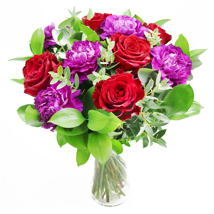 A luxurious bouquet is captured here in full, glowing detail, set within a clear glass vase that allows every clean line of the stems to show. Deep red roses dominate the arrangement, their petals densely layered and velvety, each flower at the ideal point of openness where the spiral heart is still visible but the outer petals have relaxed into soft curves. Intertwined with the roses are generous purple peonies, their rounded blooms brimming with ruffled petals that create a sense of depth and movement, as though a gentle breeze has just stirred their edges. The interplay of rich crimson and cool violet gives the bouquet a dynamic yet harmonious palette, reminiscent of vibrant front gardens dotted around Queensbury in early summer. Supporting this colour story is a generous halo of foliage, with broad, glossy leaves and slender sprigs of eucalyptus that reach upward and outward. The eucalyptus brings a silvery green accent and a graceful, arching line to the composition, helping to lighten the dense clusters of blooms. Soft natural light, like daylight filtering through a Queensbury bay window, glances off the glass and illuminates the petals, picking up subtle tonal shifts in the reds and purples. In the mind's eye, a gentle fragrance rises-a blend of classic rose, faintly spicy and warm, with the cool, fresh note of cut greenery. The effect is both timeless and contemporary, suitable for a romantic dinner at home, a special birthday gathering, or as a dramatic focal point in a lounge. The bouquet feels curated with care, expressing affection, celebration, and a touch of everyday luxury.