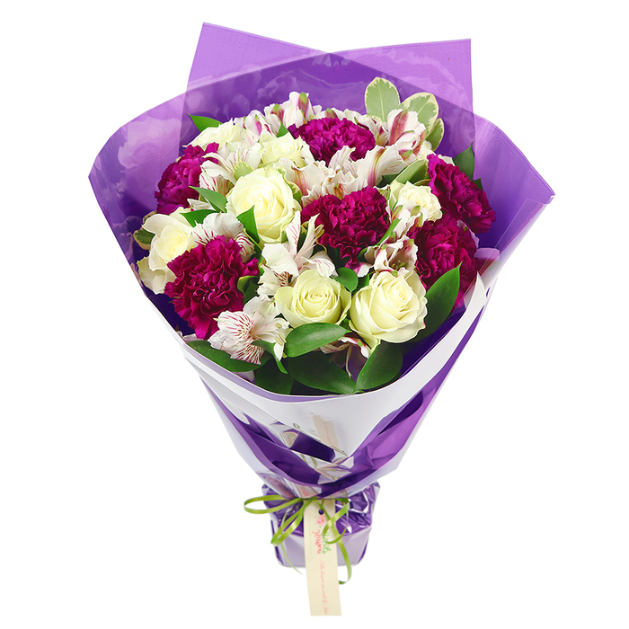 A luxurious, round hand-tied bouquet is shown standing proudly against a simple white backdrop, allowing all the intricate floristry work and colour harmony to shine. The upper part of the bouquet forms a generous, domed cluster of flowers, dominated by creamy white roses whose tightly furled centres gradually soften into layered, open petals. Woven among them are deep magenta carnations, their distinctively ruffled, almost feathery heads providing a bold contrast in both texture and tone. Between these larger blooms, slender stems of white alstroemeria peek through, their long, elegant petals etched with fine pink and pale green streaks, and each flower carrying prominent dark stamens that give a painterly, speckled finish. Fresh green foliage fills the spaces, including glossy blades and some leaves with pale, variegated margins, giving the bouquet a lively, garden-fresh feel reminiscent of the greenery seen around Queensbury's small parks and tree-lined avenues. The stems are wrapped in a structured inner collar of crisp, bright white floral paper that neatly hugs the blooms and emphasizes the bouquet's rounded shape. Over this, a layer of translucent purple cellophane or tissue has been wrapped and crinkled gently, creating soft folds that catch the light, adding both depth and a subtle, festive glimmer. The lower part of the arrangement narrows gracefully where the papers are gathered and secured with a vibrant lime-green satin ribbon, tied into a tidy bow. From this bow hangs a small, rectangular light brown tag, blank and ready to carry a handwritten greeting or heartfelt message. The bouquet radiates cheerfulness and quiet sophistication, the kind of handcrafted gift you might send to someone special in Queensbury to celebrate a birthday, anniversary, new baby, or simply to brighten an ordinary day with a touch of floral elegance.