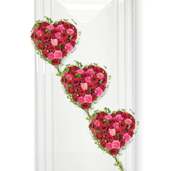 Three heart-shaped floral tributes, composed entirely of roses, appear to float down a bright white backdrop in a gentle diagonal sweep, like a quiet procession of love and remembrance. Each heart is generously filled with hundreds of roses in tones of deep crimson, ruby red, vivid fuchsia, and soft blush pink, their tightly clustered petals forming a plush, almost fabric-like surface. The red blooms carry a sense of loyalty, passion, and lifelong commitment, while the pinks bring comfort, gratitude, and warmth, as if echoing fond words shared at a service in a Queensbury church or a farewell gathering near the local park. Around the edges, fine trails of ivy weave an elegant outline, the fresh green leaves adding a living contrast to the saturated reds and pinks. These slender vines extend delicately between the hearts, visually tying them together so they feel like chapters of one story-perhaps partners, parent and child, or three generations honoured together. The hearts are stacked from top left to bottom right with a slight tilt, creating a graceful downward flow that suggests movement without haste, suitable for a calm moment of reflection. The white background is smooth and unadorned, reminiscent of a polished panel in a quiet funeral home or crematorium near Queensbury, ensuring all attention rests on the flowers' rich textures and colours. Soft, even lighting reveals every curve of the rose petals and the gentle gloss of the ivy leaves. This image conveys the skilled artistry of a dedicated florist, evoking sympathy, remembrance, and an enduring promise of love that continues beyond goodbye.