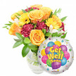 A bright, uplifting 'Get Well Soon' arrangement set against a crisp white background, the kind of comforting bouquet I would tuck into a delivery bag at Queensbury Underground station on a gentle morning. To the left, a generous cluster of soft orange and warm yellow roses opens in large spirals, their petals catching the light and offering a subtle citrus-rose scent. Interspersed are sunny yellow gerbera daisies with distinct dark centers, their flat, cheerful faces tilting slightly as if nodding encouragement. Deeper burgundy or maroon carnations provide a ruffled, velvety contrast and add tactile depth, while small sprays of white alstroemeria tuck between blooms like delicate sighs of calm. Glossy green foliage-broad leaves and feathery filler-frames the composition and gives the bouquet a fresh, garden-picked feel; stems sit visible in a clear glass vase so you can see the water and how the flowers are carefully arranged. At the lower right, partially overlapping the blooms, a shiny round Mylar balloon reflects soft highlights; its silver surface holds a playful cluster of cartoon-style balloons in blue, purple, green, pink, and yellow, patterned with stripes and dots. Bold yellow-and-blue lettering reads Get Well Soon with a slight shadow, while tiny starbursts and a discreet KALEIDOSCOPE logo near the balloon's rim complete the message. Bathed in soft daylight, this ensemble radiates optimism and gentle care-perfect for sending to a neighbour recovering at home in Queensbury, a thoughtful pick-me-up after a hospital visit, or a bedside surprise to lift spirits with colour and warmth.
