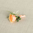 Set against a finely woven, light beige linen, this handcrafted boutonniere presents a single apricot-peach rose as the focal point, its petals curling inward in a compact spiral that opens to softer, velvety outer edges. The colour moves from a concentrated orange-salmon at the heart to pale, creamy tips, catching diffuse daylight that highlights the bloom's tender texture. Surrounding the rose, clusters of tiny white gypsophila breathe an ethereal softness into the arrangement, their pinpoints of white creating the impression of a gentle, celebratory rain. Complementary foliage-slender blades of vivid green grass and a pair of darker, looped leaves-are folded and positioned to frame the blossom, adding sculptural balance and a cool, leafy counterpoint to the warm petals. The stems are wrapped in a coordinating peach satin ribbon and finished with a discreet silver pin near the base, a practical flourish that shows the piece is ready to be attached to a lapel. As a Queensbury florist I think of neighbours selecting this for weddings at nearby community halls or for prom nights on Kingsbury High Road; its modest size and timeless palette suit both intimate and formal occasions. The satin's smooth texture, the rose's faint honeyed aroma and the linen's tactile cross-hatch combine to create an object that feels as comforting to hold as it looks refined to wear. Available for local collection or same-day delivery across Queensbury, Kingsbury and Wembley, it's a quietly elegant choice that balances classic tradition with careful, local craftsmanship from Flower Delivery Queensbury.