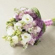 A beautifully hand-crafted bouquet by a Queensbury florist, this arrangement features the timeless elegance of fresh white Lisianthus in lush, pillowy bloom, each petal softly layered around a creamy yellow heart. Interspersed among these are clusters of airy Stock flowers in pastel pinks and gentle lavender shades, creating a harmonious blend of colors that evoke springtime strolls through local parks. Deep purple Allium 'Star of Persia' adds dramatic flair and bold spherical texture, peeking between the more delicate petals and echoing the spirit of vibrant Queensbury gardens. Rich green foliage and slender Lisianthus buds are woven expertly throughout, introducing brightness and structure to this rounded, slightly elongated bouquet. The neatly gathered stems are immaculately finished with a striking fuchsia pink satin ribbon, elegantly wrapped in a delicate white pearl strand-a subtle nod to the sophistication of community celebrations. With the bouquet resting on a soft, neutral surface and illuminated by even, natural light, every detail shines: from the gentle ruffles of Stock to the unmistakable starburst accents of Allium. Perfect as a bridal bouquet, centerpiece, or heartfelt gesture delivered anywhere in Queensbury, this floral composition radiates romance and refined artistry, reflecting the modern tastes and traditions of the area.