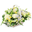 A light-toned wicker basket with a tall, matching handle is filled to overflowing with soft, pastel funeral blooms, posed against a crisp white background that makes every petal and leaf stand out. The composition forms a rounded dome, with large, creamy white roses positioned prominently at the centre, their fully opened petals curling outward in smooth, elegant layers. Around them, smaller white and pale yellow flowers, similar to freesia, cluster in gentle sprays; some blossoms are open and lightly fragrant in appearance, while others remain as closed buds, adding varied shapes and a sense of quiet anticipation. Interspersed among these are striking star-shaped clematis in shades of pale lavender and light periwinkle blue, each bloom marked by a vivid yellow-green heart that draws the eye without disturbing the soft, restful colour scheme. The basket is richly framed by deep, glossy green foliage, including broad, sturdy leaves and finer, more delicate greenery that threads through the flowers, evoking the look of a thoughtfully tended garden. The neutral wicker, in white or light beige, adds a simple, homely grace, similar to the classic sympathy arrangements chosen for services and home deliveries throughout Queensbury. The mood of the image is calm and consoling, making this floral basket ideal for funerals, memorial gatherings, or condolence visits to families along Church Lane and surrounding streets, where its gentle colours and textures can offer a quiet gesture of care and remembrance.